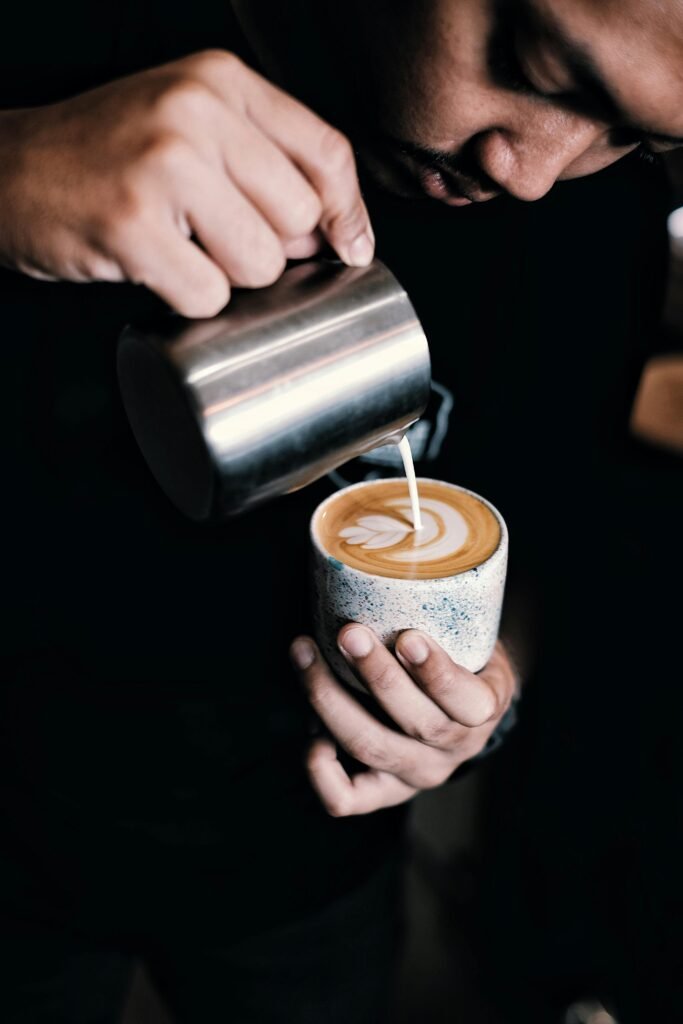 Close-up of a barista creating latte art with precision and skill in a coffee cup.