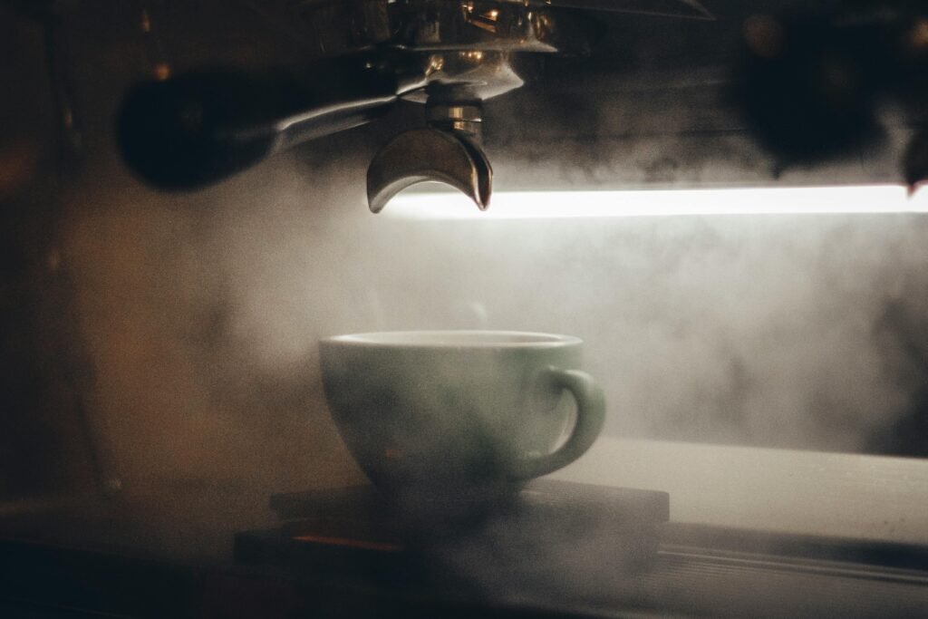 Close-up view of a steaming cup of espresso being brewed by a coffee machine, creating a warm and inviting atmosphere.