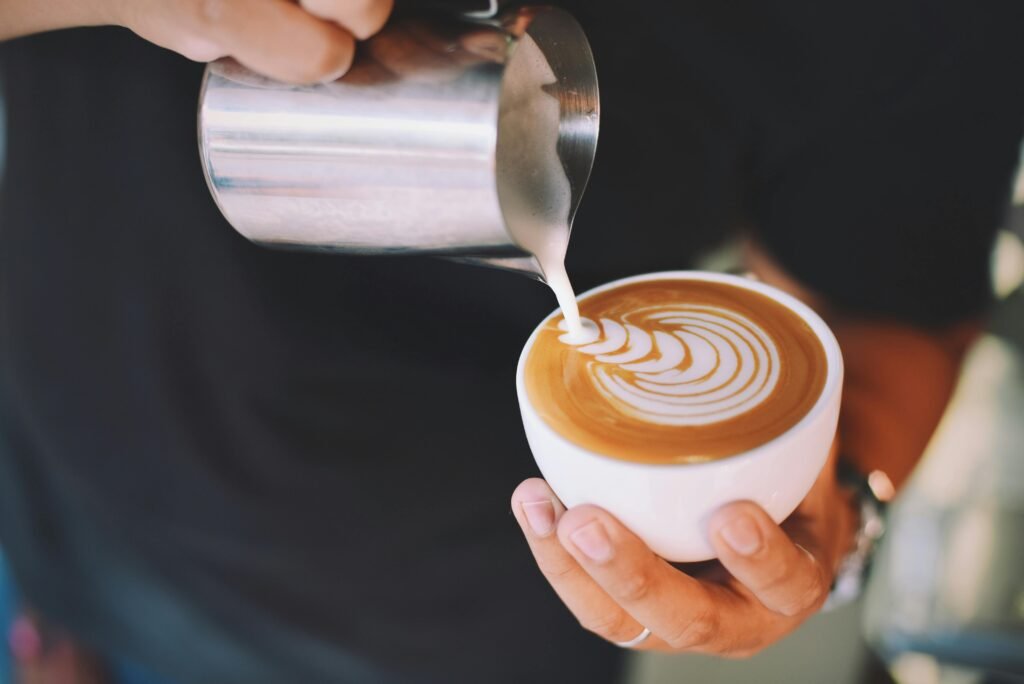 Captivating image of a barista pouring milk art into a cappuccino cup, showcasing latte art skills.