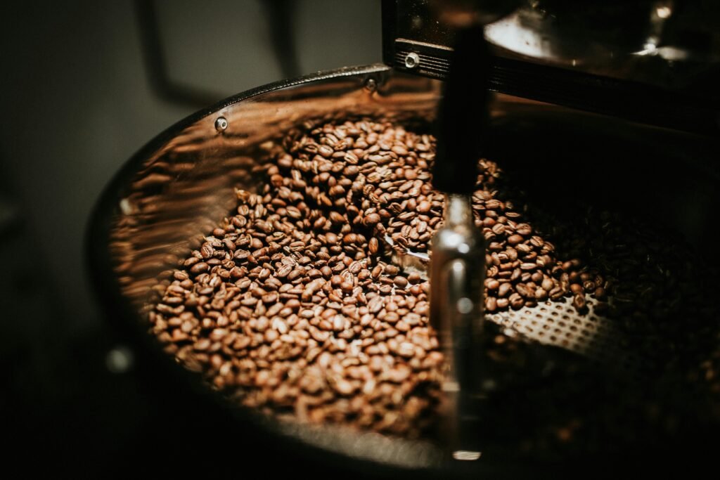 Close-up of freshly roasted coffee beans in a large industrial coffee roaster, showcasing rich textures and warm tones.